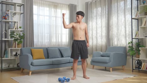 full body of asian teenager boy flexing his bicep after doing shirtless workout at home