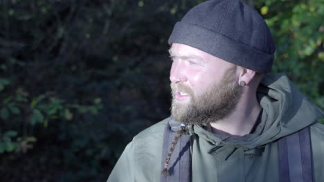 adult man with beard lighting by sunlight without orientation looking around in forest