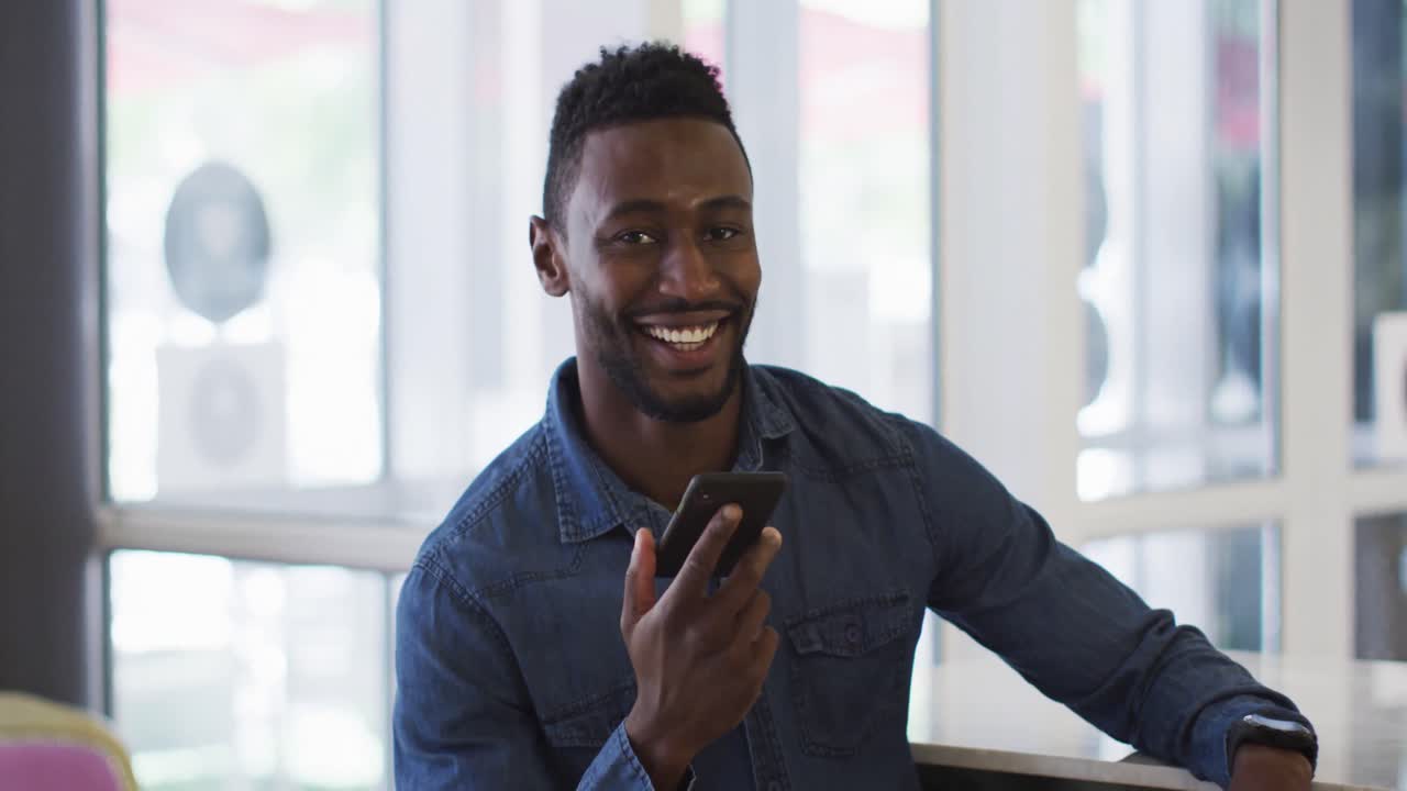 Smiling african american businessman talking on smartphone in cafe