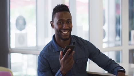 Lächelnder-Afroamerikanischer-Geschäftsmann,-Der-Im-Café-Auf-Dem-Smartphone-Spricht