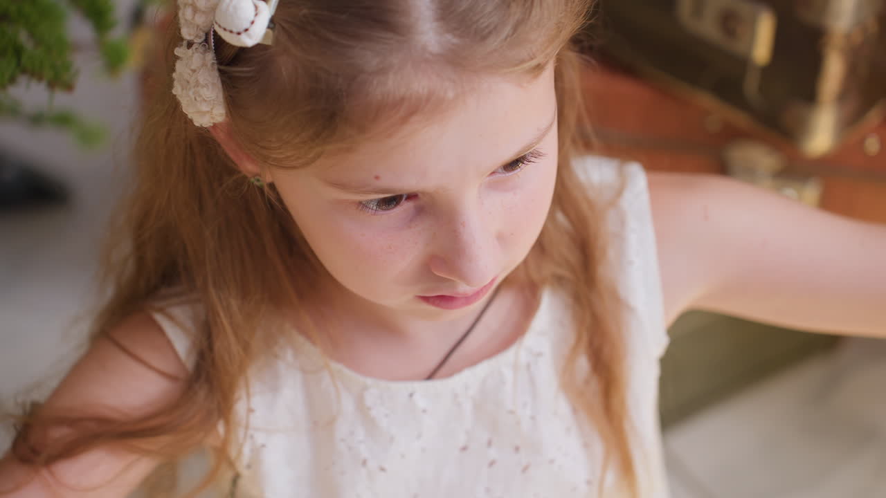 Close-up view of little girl in white gown with flower in her hair, holding Christmas lights, preparing for festive decorations with family for holiday celebrations and joy