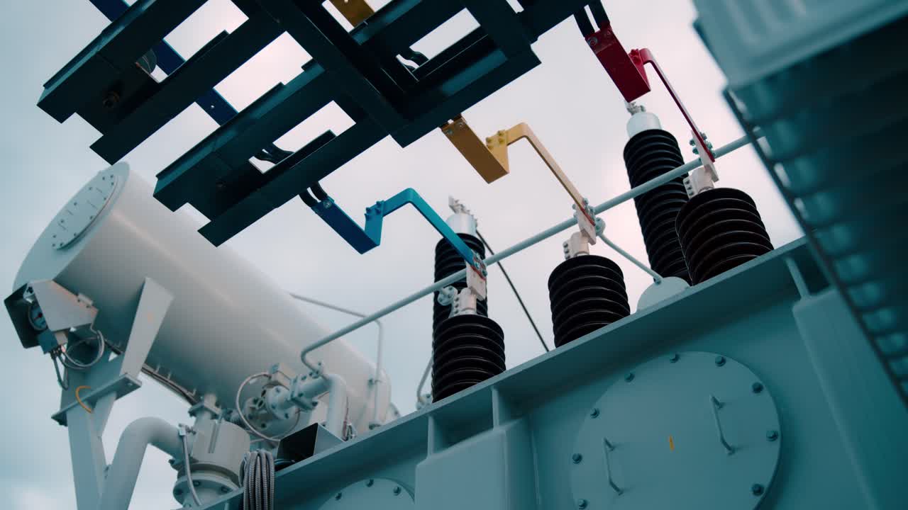 Upward view of transformer with cables against cloudy sky, industrial setting