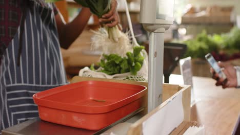 sección media de un hombre afroamericano de alto nivel pagando con un teléfono inteligente en una tienda de alimentos saludables, cámara lenta