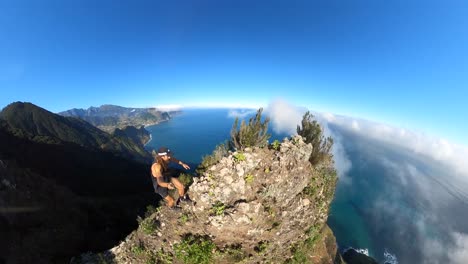 un excursionista solitario joven y fuerte camina por el borde empinado de espigao amelo en madeira con una cámara de acción de 360 grados en un palo selfie con una vista increíble del paisaje y el océano debajo de él