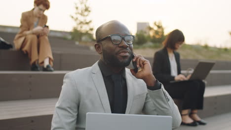 Black-Businessman-Speaking-on-Phone-while-Working-Outdoors