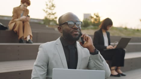 black businessman speaking on phone while working outdoors