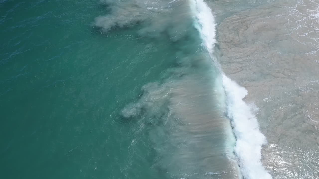 Aerial View of Turquoise Ocean Waves Crashing on White Sand Beach