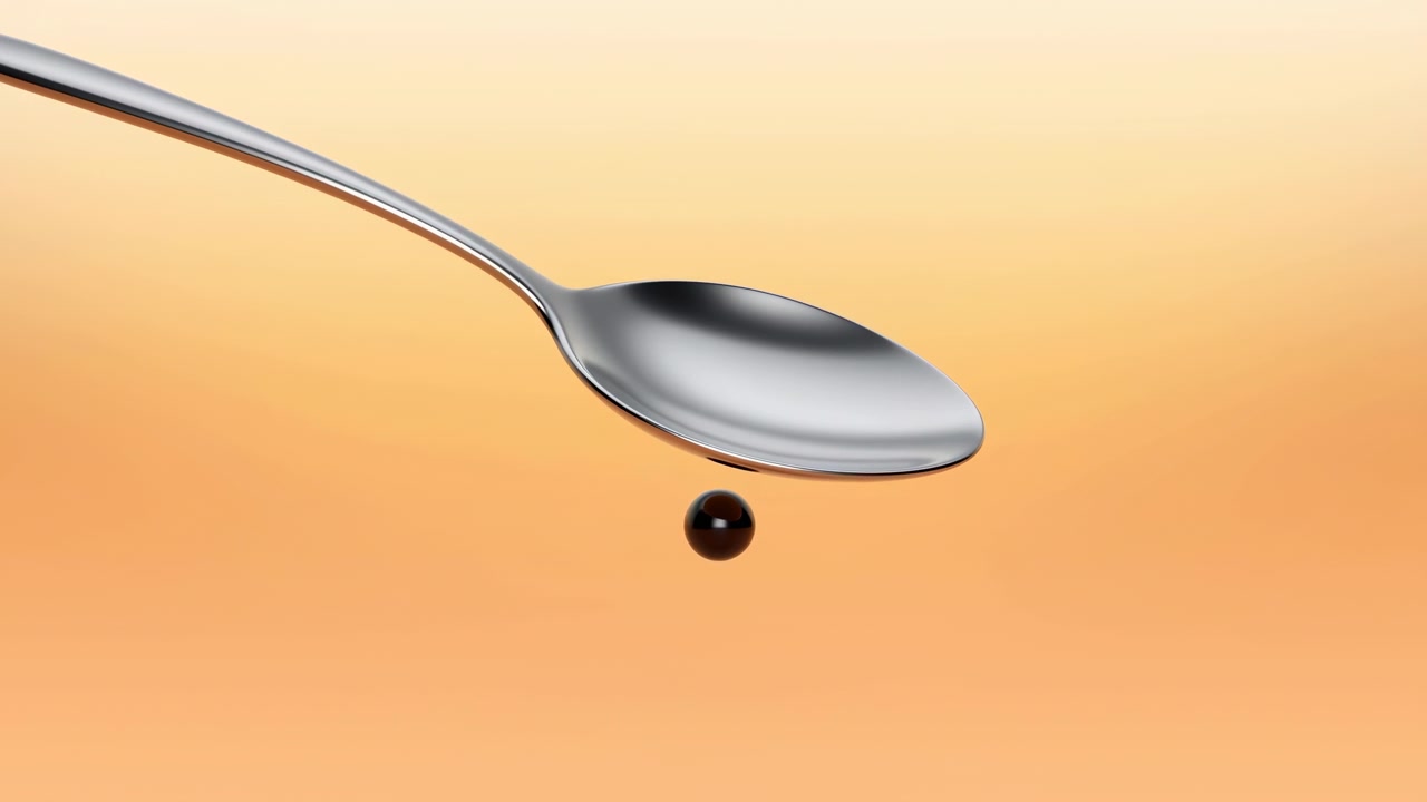 Close-up of a silver spoon with a single dark droplet suspended beneath it against a warm orange gradient background, with soft even lighting and ample negative space