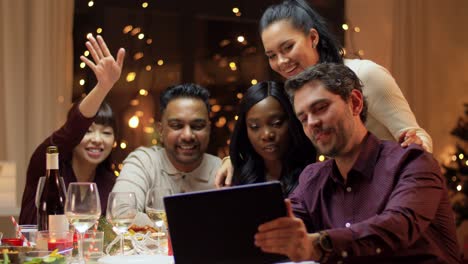 Vacaciones-De-Invierno,-Celebración-Y-Concepto-De-Personas.-Amigos-Felices-Con-Una-Computadora-Tablet-Haciendo-Una-Videollamada-En-La-Cena-Navideña-En-Casa.