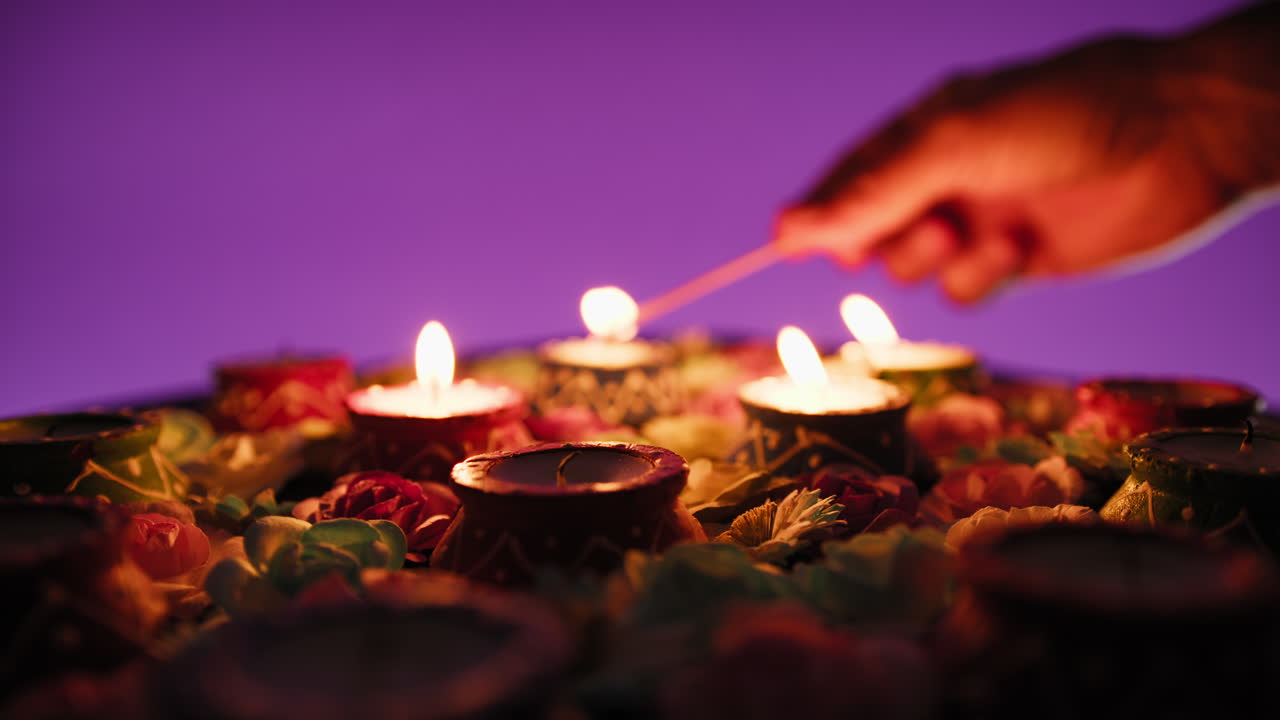Silhouette of hand lighting candles amidst flowers for Diwali