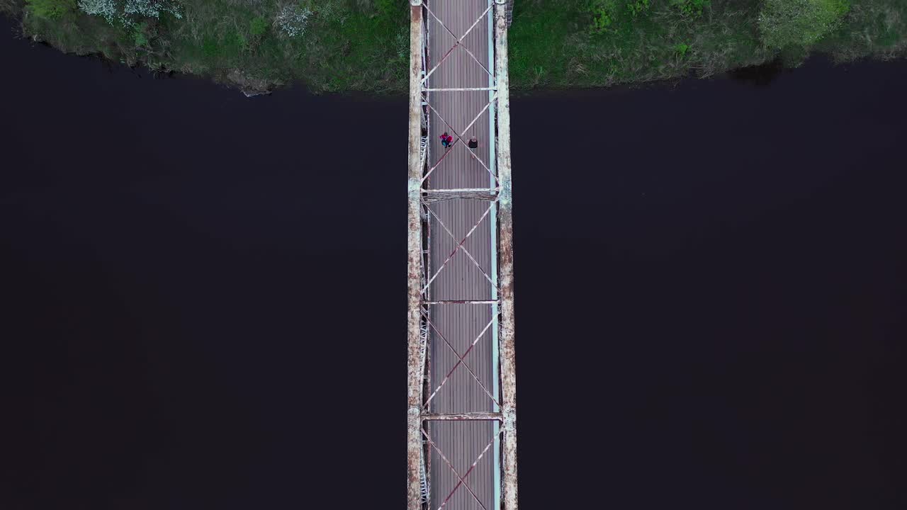 Couple walking on pedestrian bridge over river Gauja in Latvia, top down view