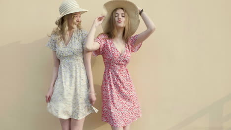 two happy women in floral dresses and straw hats