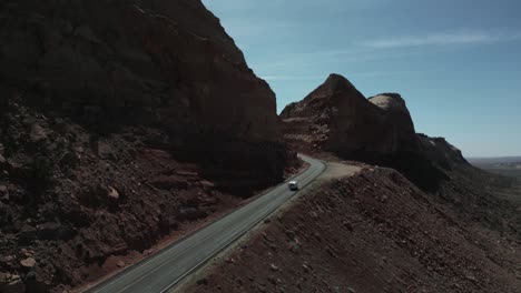 camper van driving on the road with sandstones mountains in deserts of utah, united states