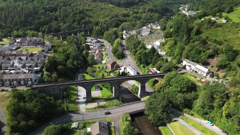 an aerial sideways drone shot of a beautiful welsh village with a viaduct on a summer's day