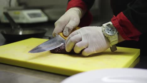 chef cortando un bistec y colocándolo en un plato con vegetales para servir