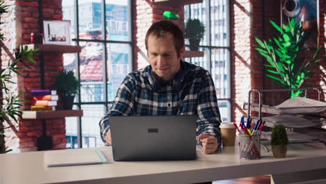 man enjoying leisure time at home, texting friends on laptop