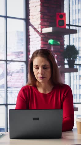 vertical video casual focused woman sitting at her desk and reading research papers
