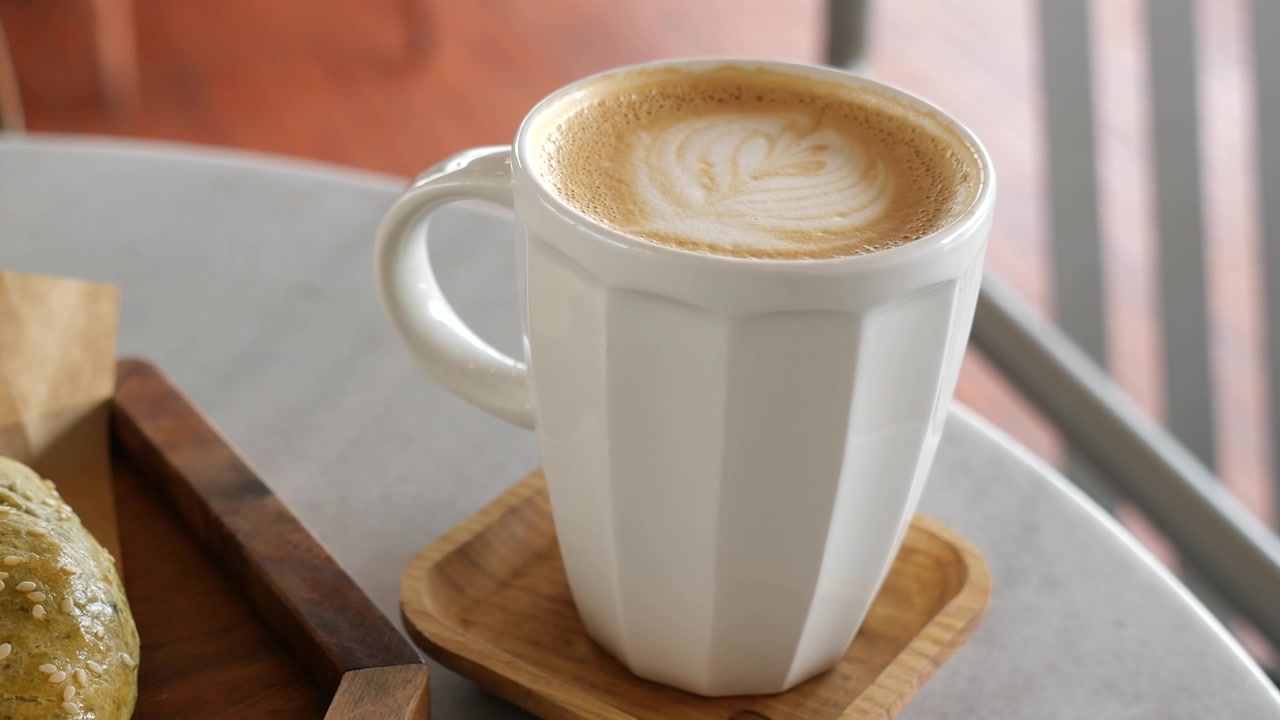Tazza bianca di latte macchiato con latte art su un tavolo da caffè