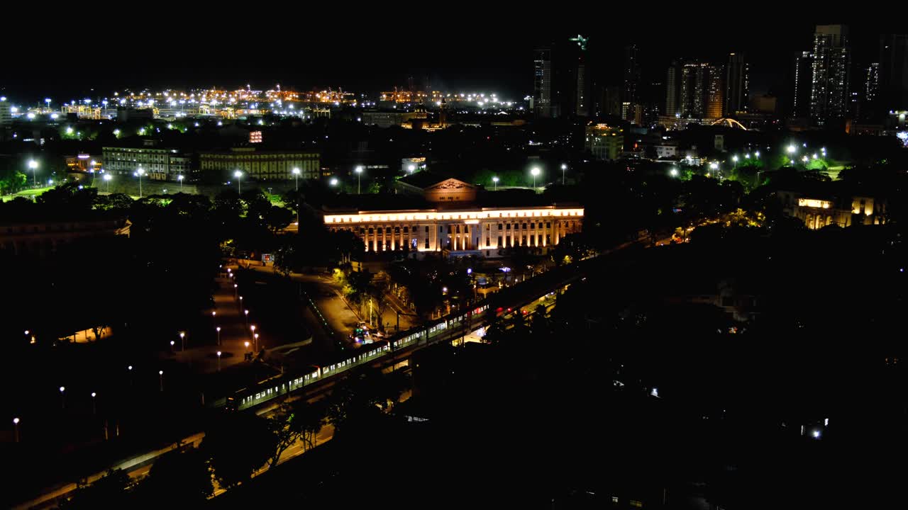 Aerial view of capital city skyline of Manila Philippines with night lights of metropolis train passing National Museum of Fine Arts and historical Intramuros Walled City