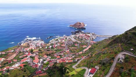 Aerial-tilt-up-reveal-of-Porto-Moniz-city-on-Madeira-coastline-in-summer