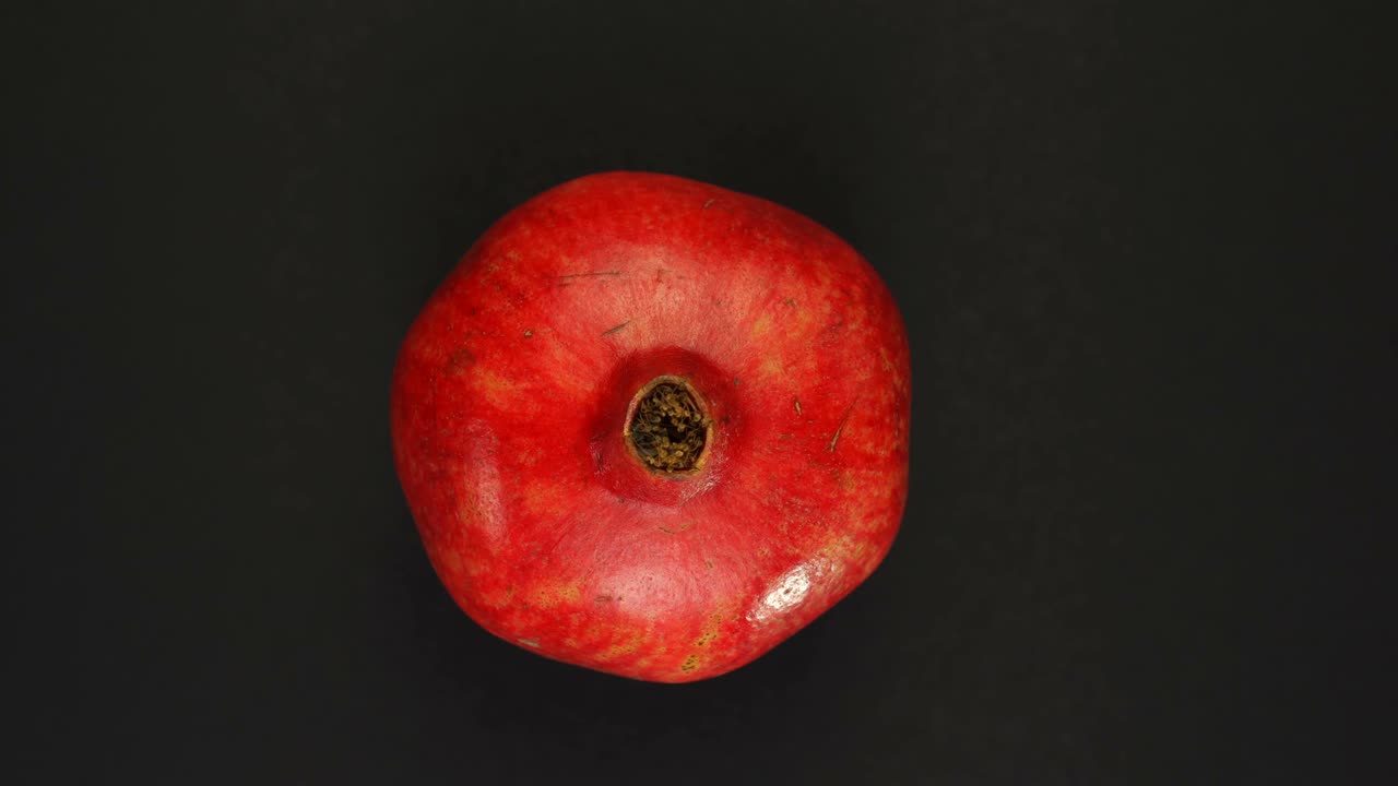 Roterende granatæble eller punica granatum på en sort baggrund isoleret. Friske juicer, frugter, vitamin- og sommerkoncept