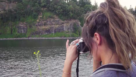 linda chica hipster jugando con una cámara de cine en un parque