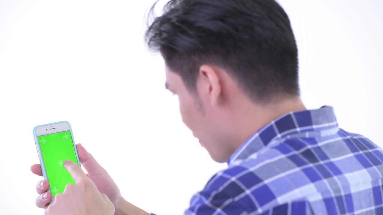 색 배경에 고립 된 녹색 화면으로 전화를 사용하는 젊은 잘생긴 아시아 남자의 초상화