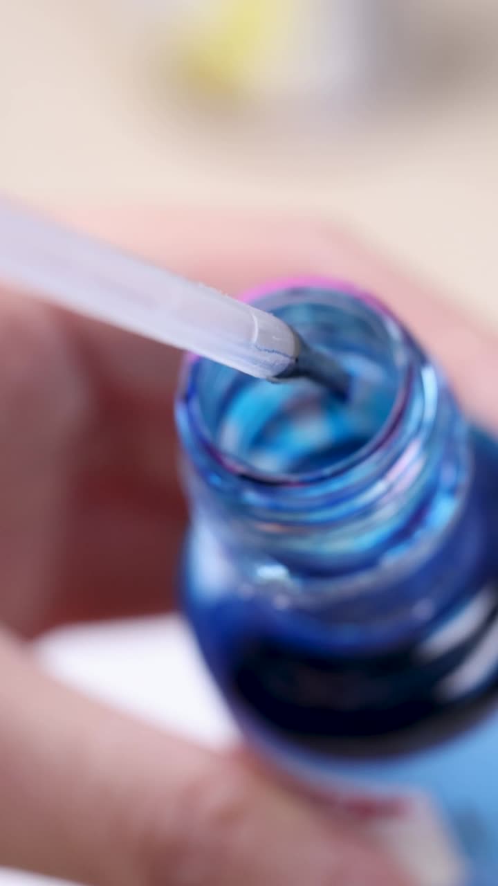Scatto macro verticale di una mano che usa una pipetta per estrarre colorante alimentare blu