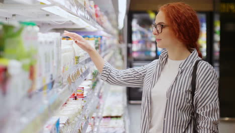 kaukasische junge frau wählt joghurt in einem supermarkt