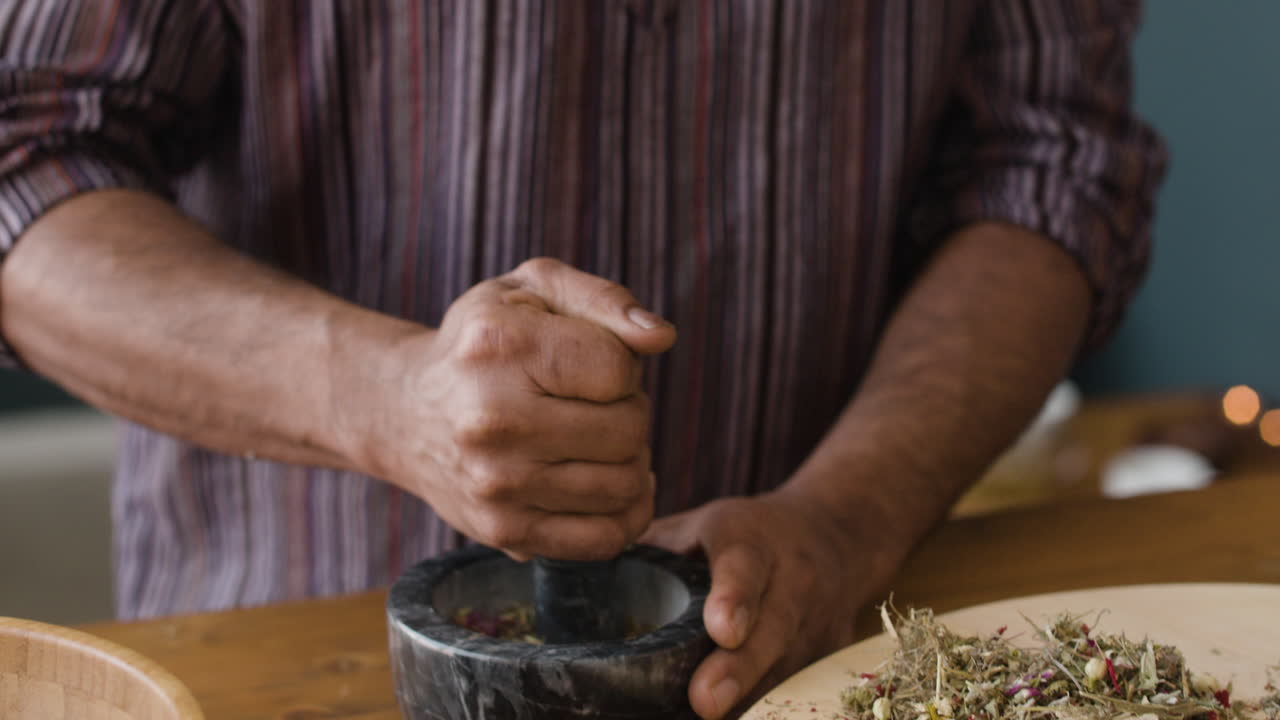 Man crushing herbs in a mortar and pestle