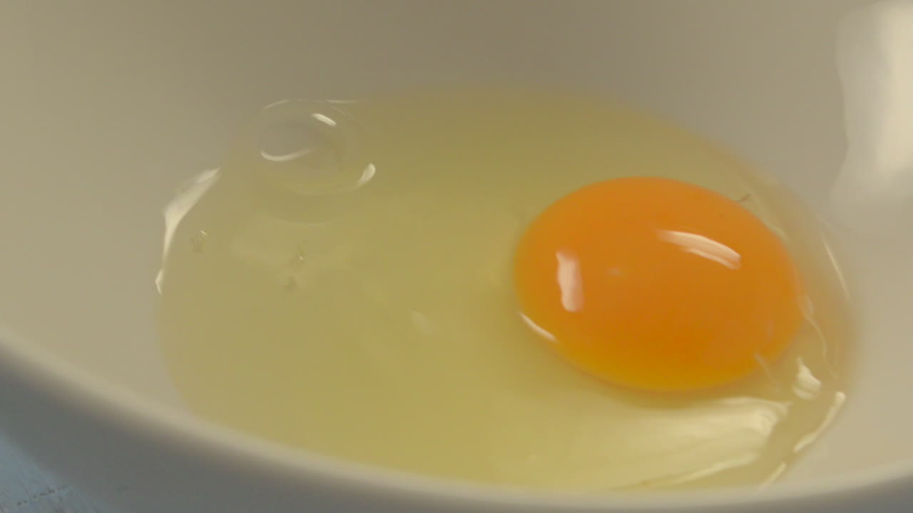 One egg falling into bowl in slow motion
