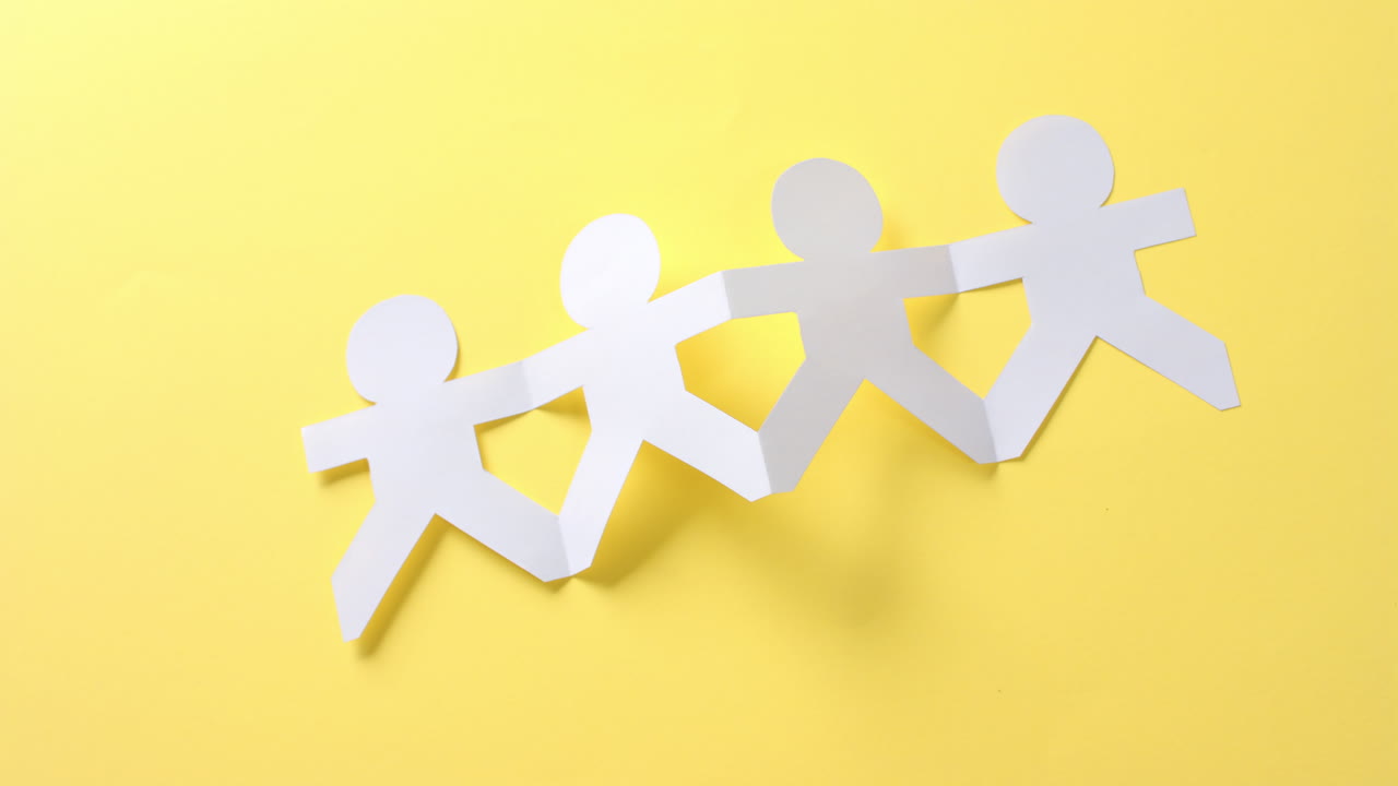 복사 공간과 함께 노란색 배경에  ⁇  종이로 만들어진 손을 잡은 사람들의 클로즈업