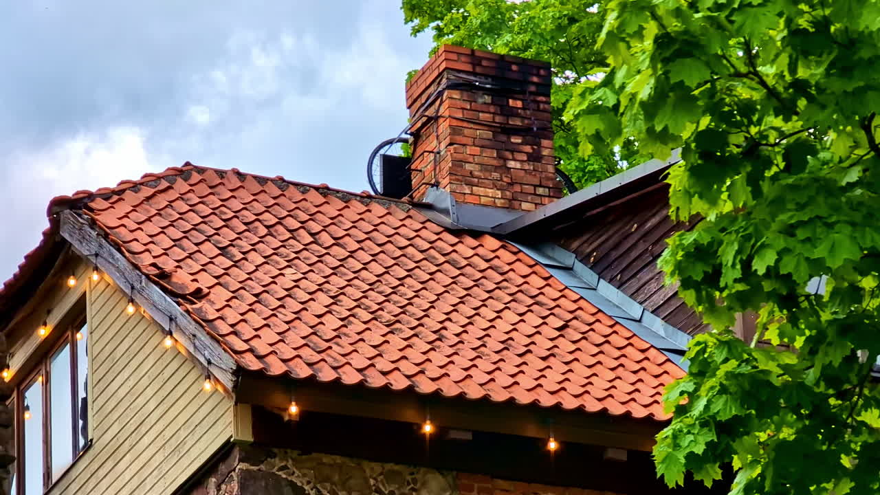 Rooftop with red tiles and old brick chimney among trees