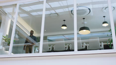 Joven-Hombre-De-Negocios-Afroamericano-Sonriendo-Confiado-Mirando-Por-La-Ventana-De-La-Oficina-Con-Los-Brazos-Cruzados-Disfrutando-Del-Liderazgo-Corporativo-Joven-Empresario-Planeando-Con-Anticipación-Para-Un-Futuro-Positivo-Imágenes-De-4k