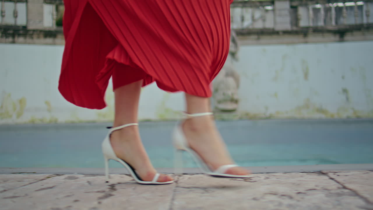 Red dress woman legs walking fountain spinning closeup. Fashionista going date