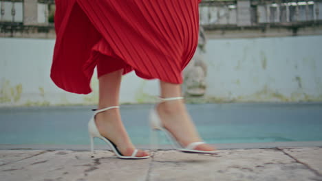 red dress woman legs walking fountain spinning closeup. fashionista going date