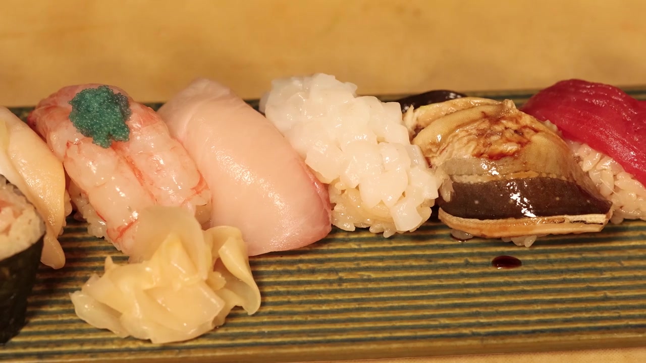 Primo piano di sushi nigiri assortiti serviti con zenzero marinato su un piatto di ceramica