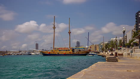 Valletta,-Malta-with-a-large-wooden-Navy-sailing-ship-docked-on-the-waterfront---time-lapse