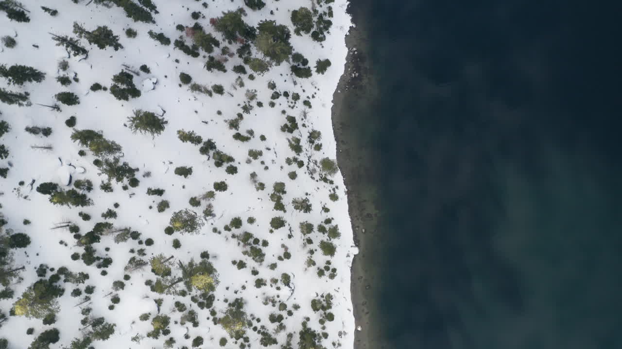 경사면에 폭설이 내리는 에메랄드 베이 해안선의 하향 공중