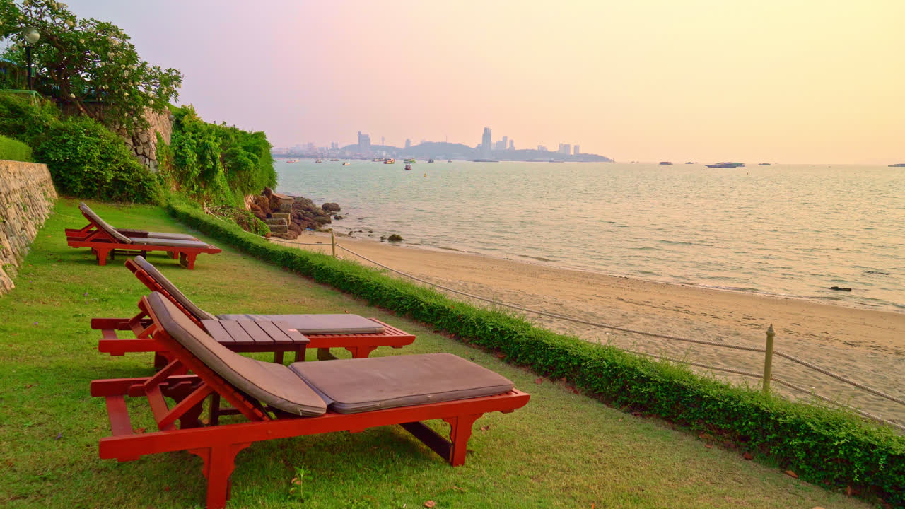 해질녘 바다를 배경으로 한 해변 의자 또는 풀 침대와 파라솔