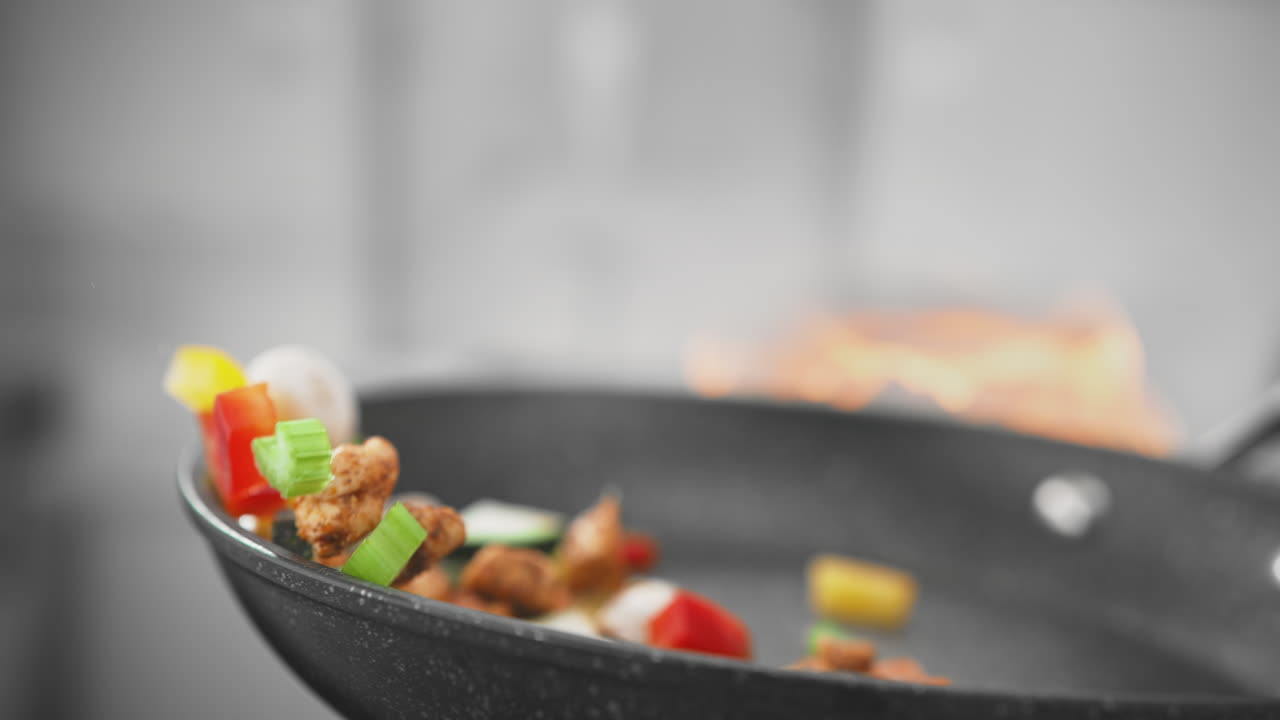 cocinar comida asiática - pollo con hongos y verduras arrojados en un wok sobre el fuego en cámara lenta