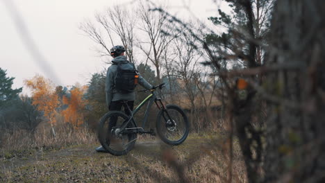 athlet mann, der sich vom reiten eines mountainbikes in der landschaft ausruht