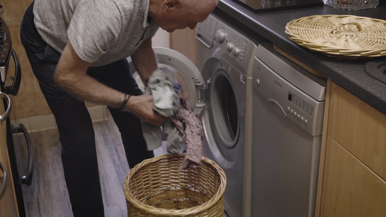Senior man doing laundry in the kitchen