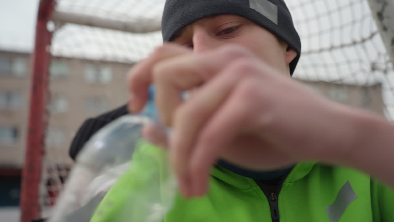 코칭 지침을 흡수하는 팀원, 동료로부터 전술 지시를 주의 깊게 받는 운동선수, 추운 날씨에 대비한 복장을 하고 골대 근처에서 코칭 교류에 집중하는 참가자