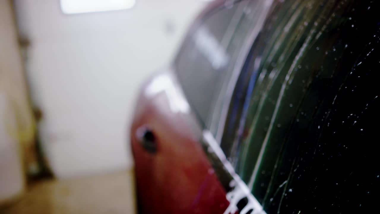 Spraying water washing soap off car roof