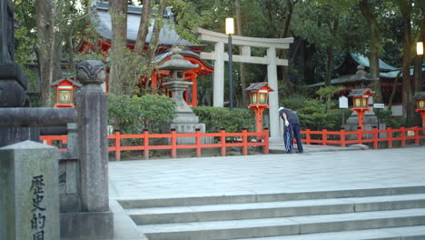 chico temprano en la mañana limpiando un hermoso santuario en kyoto, japón iluminación suave