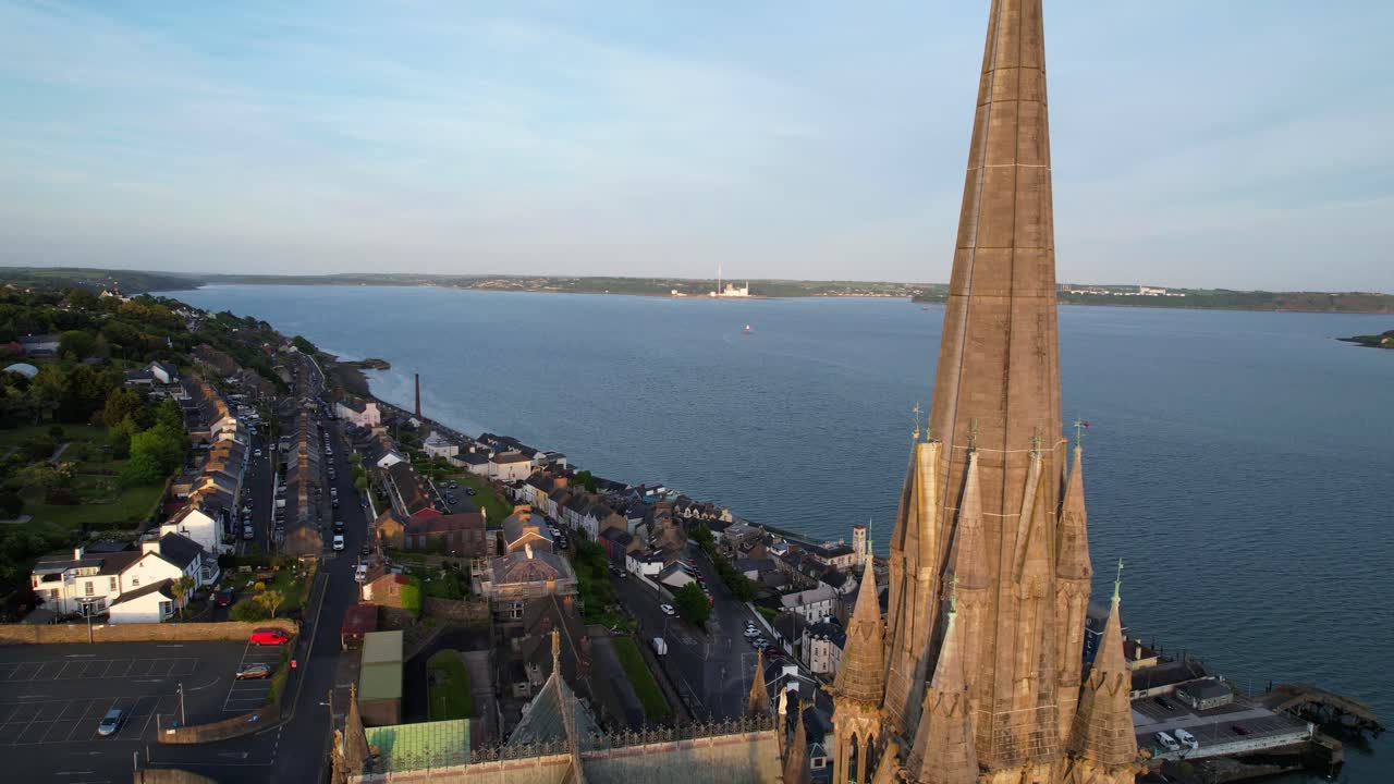 Aerial dolly out revealing Cobh bay and St Colman's Cathedral at sunset, Ireland