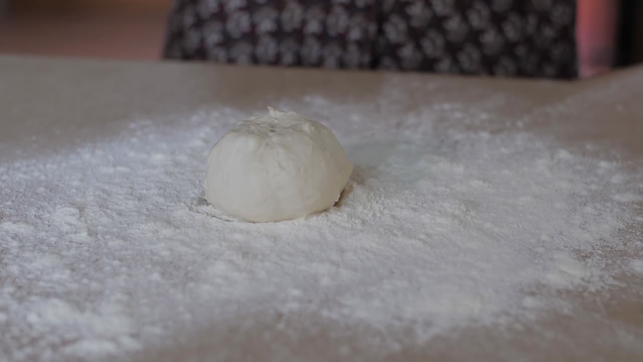 Dropping a ball of bread dough onto a floured surface