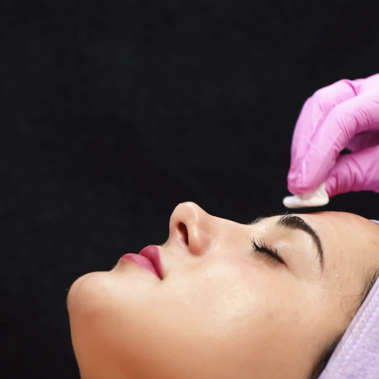 Female cosmetologist using ultrasonic scrubber on client's face. Professional ultrasonic equipment. Face cosmetic procedure.