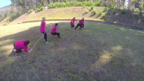 grupo de mujeres jugando al tira y afloja durante un entrenamiento de obstáculos 4k